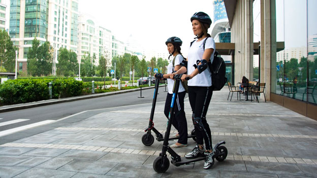 Zwei Frauen mit Helm auf E-Scooter
