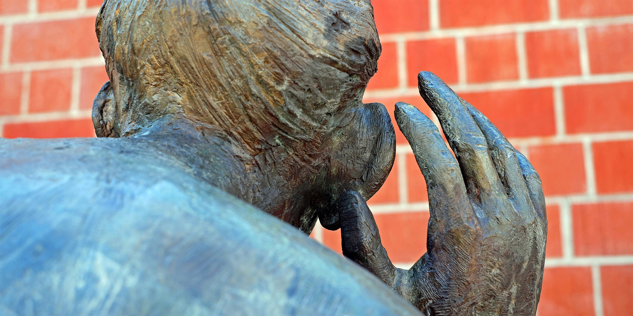Bronzeskulptur: Person hält Hand ans Ohr, um besser zu hören
