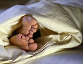 Füße ragen unter einer Bettdecke hervor
