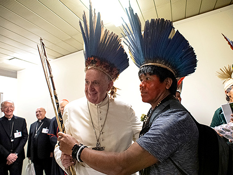 Papst Franziskus mit einem Vertreter Indigener aus der Amazonas-Region und Kopfschmuck