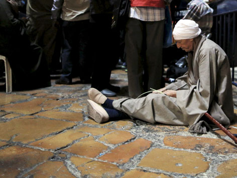 Ein Mann sitzt auf dem Steinboden der Grabeskirche in Jerusalem