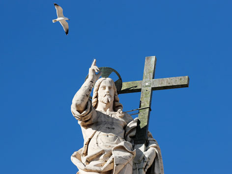 Eine Möwe kreist um eine Jesusstatue in der Nähe des Petersplatzes in Rom