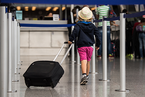 Ein Kind mit Strohhut zieht seinen Koffer am Flughafen Frankfurt