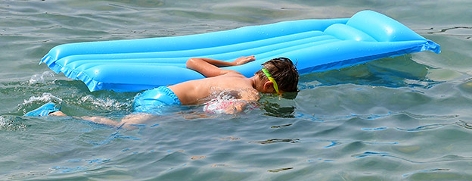 Kind mit Luftmatratze im Wasser