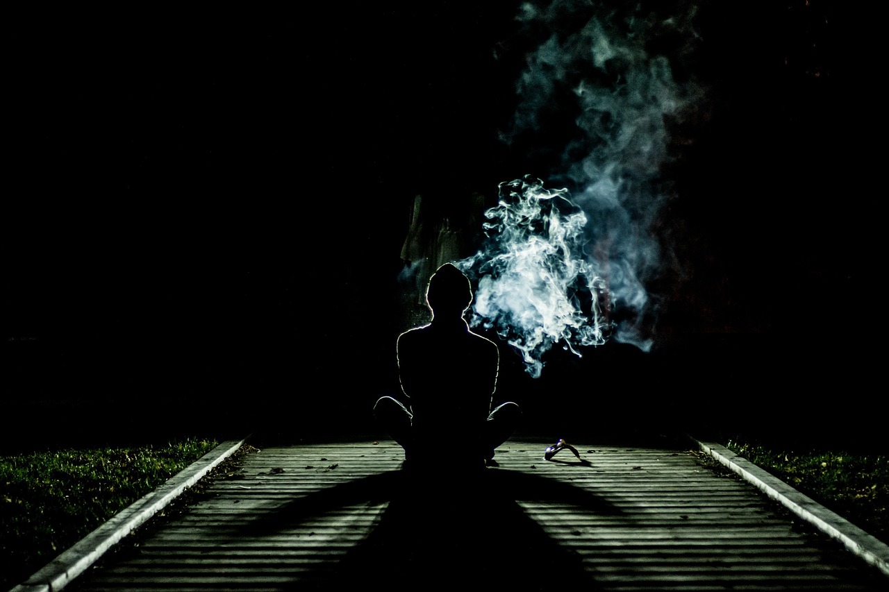 Rauchende Person von hinten im Dunkeln
