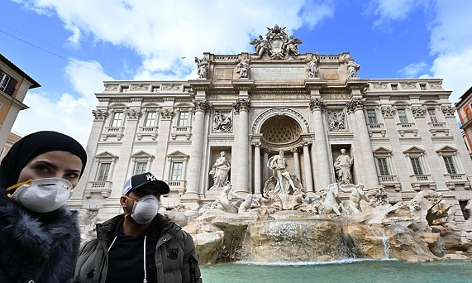 Touristen mit Atemschutzmasken vor dem Trevi-Brunnen in Rom