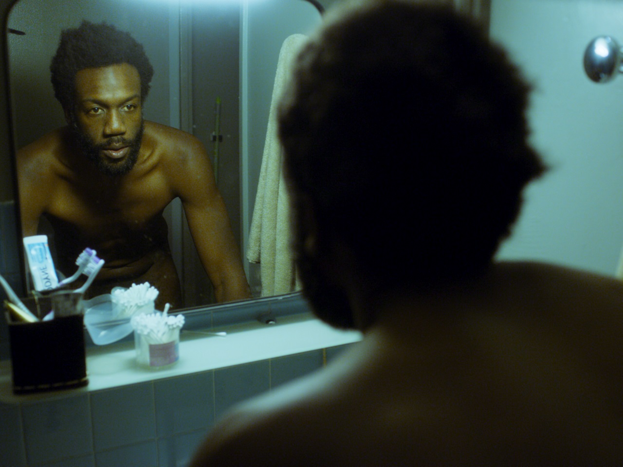 Ein Mann steht nackt in seinem Bad und schaut sein Spiegelbild an. Filmszene aus "The Blindspot".