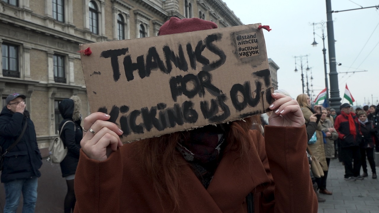 Eine Demonstrantin hält ein Schild hoch, auf dem steht: "Thanks for kicking us out". Filmszene aus der Dokumentation "The Free University".