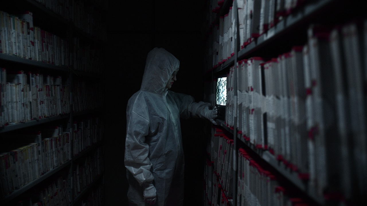 Eine Frau im Schutzanzug steht in einem großen Archiv. Filmszene aus "The Sound is innocent".