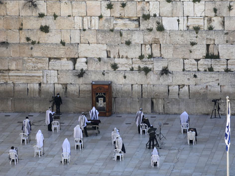Die Klagemauer in Jerusalem mit einzelnen Sesseln und Betenden. Betende werden  beschränkt und unter Wahrung des Sicherheitsabstands zugelassen