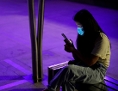 Eine junge Dame mit Maske und Handy in Wuhan