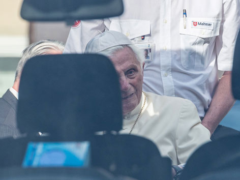Benedikt XVI. wird im Rollstuhl zum Auto geführt