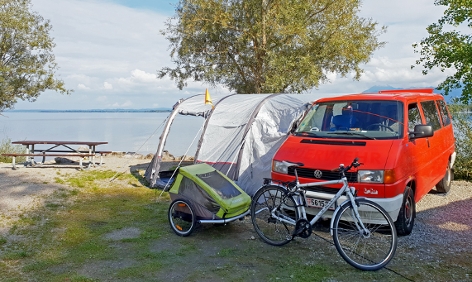 Ein Campingbus mit Vorzelt auf einem Campingplatz am See