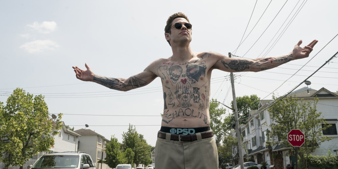 Mann mit vielen Tattoos steht mit ausgebreiteten Armen auf einer Straße