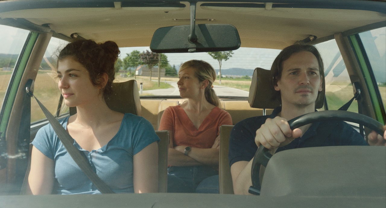 Elisabeth Wabitsch, Martina Poel und Christopher Schärf fahren in einem Auto durch Felder, eine Filmszene aus "Siebzehn".