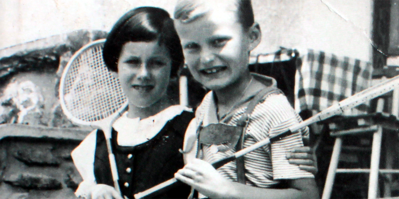 Schwarz-Weiß-Fotografie: Bub und Mädchen mit Tennisschlägern