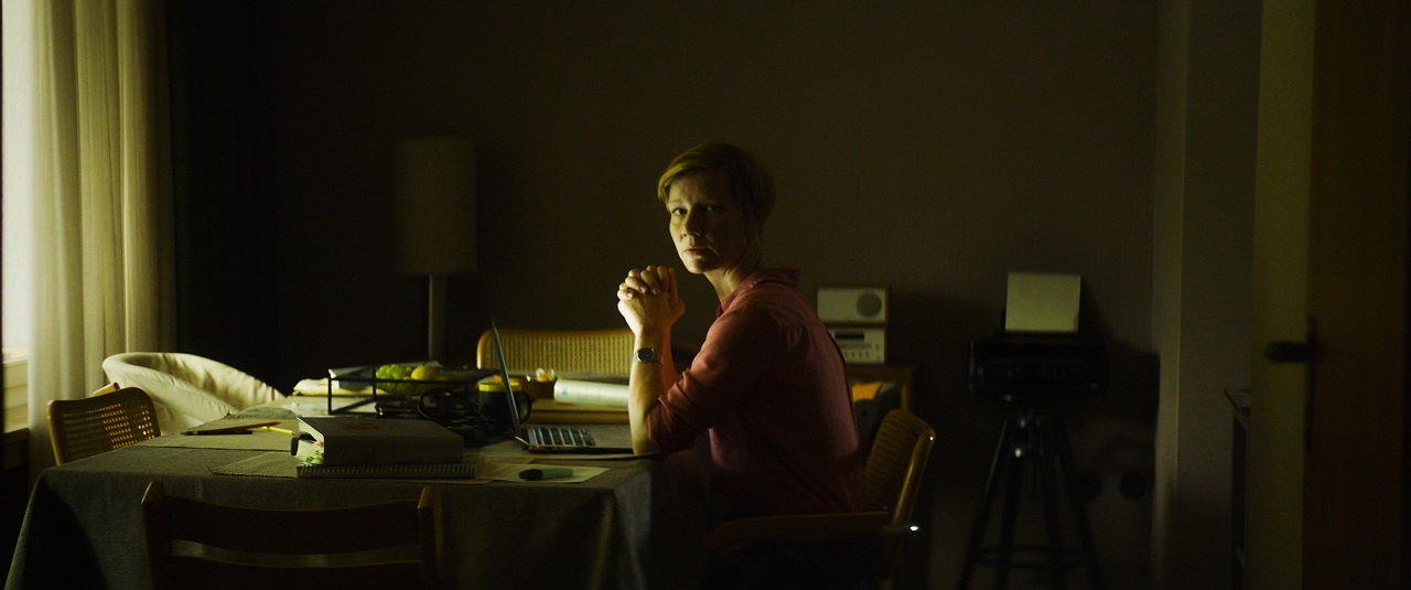 Sandra Hüller sitzt an einem Schreibtisch und schaut zur Seite, wer in den Raum kommt. Szene aus dem Film "Exil".