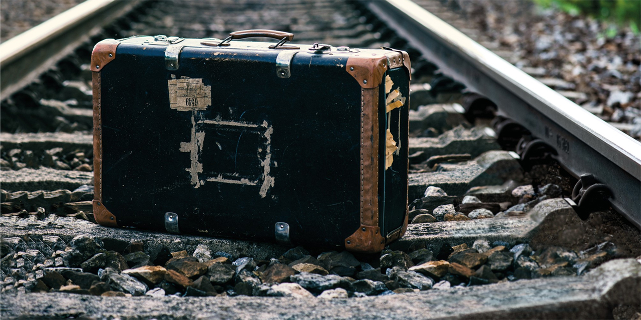 Ein Koffer steht auf Eisenbahngleisen