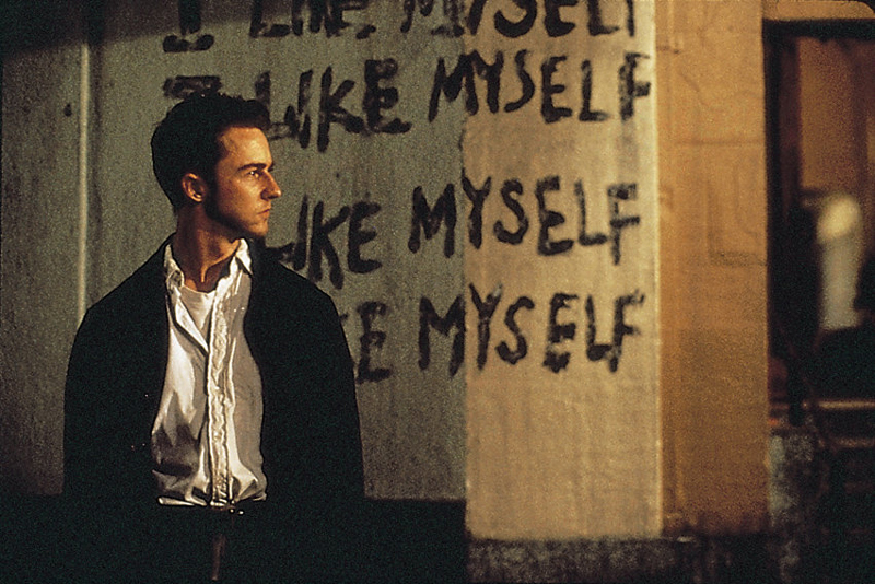 Ein Mann steht vor einer Hauswand, auf der steht: "I like myself"