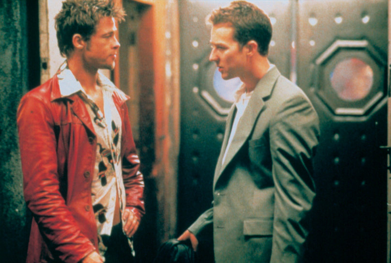 Zwei Männer im Gespräch, einer trägt eine rote Lederjacke, der andere einen grauen Business-Anzug