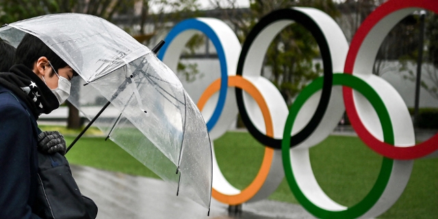Japaner mit Regenschirm vor den Olympischen Ringen in Tokio