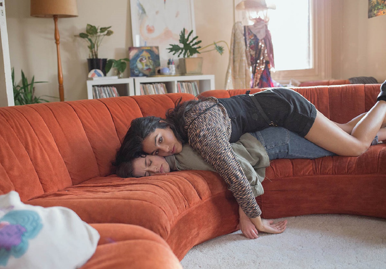 Zwei Freundinnen liegen erschöpft auf einer Couch, die eine auf dem Rücken der anderen. Aus der Serie "Why Are You Like This".