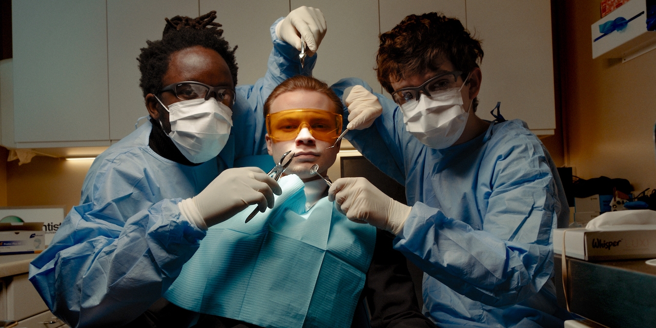 black midi, drei Bandmitglieder sind als Zahnärzte & Patient dargestellt