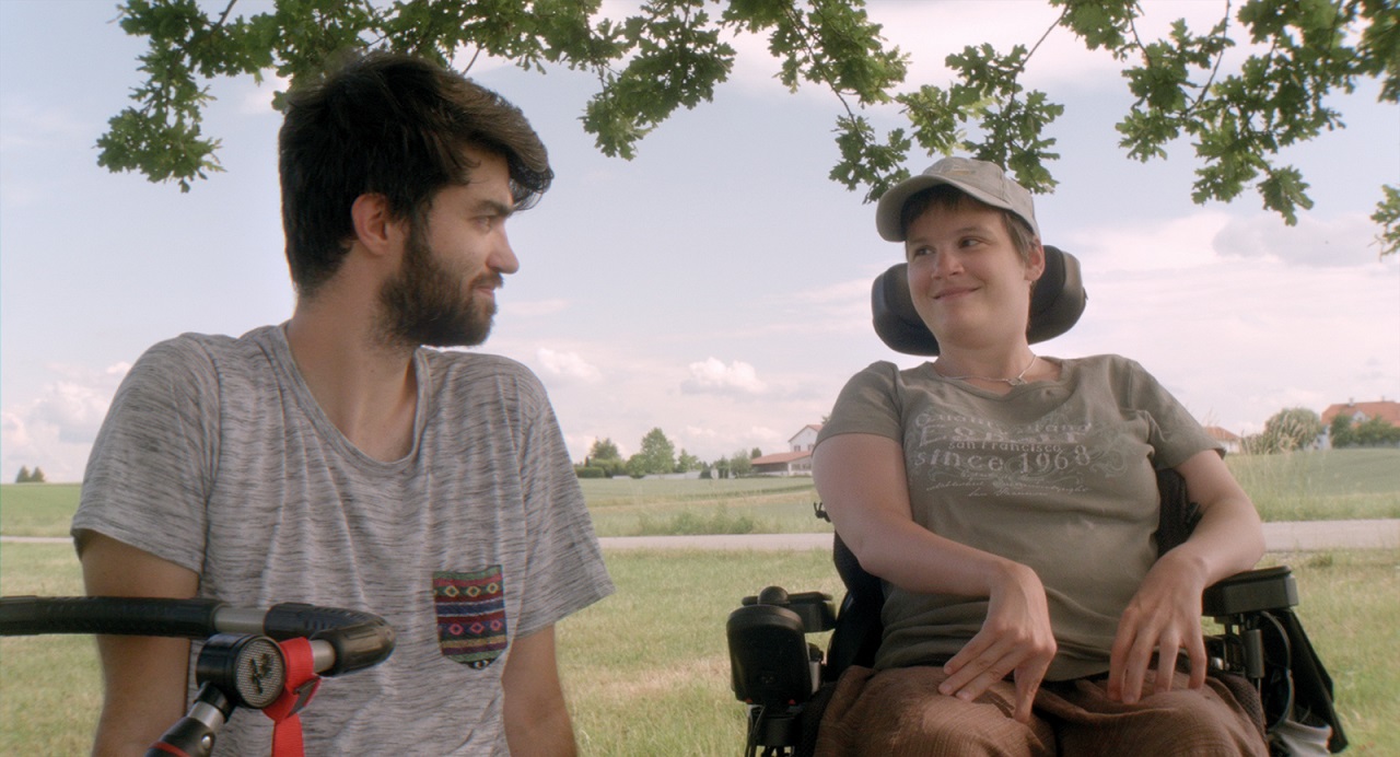 Filmemacher und persönlicher Assistent Lukas Ladner und Eva-Maria sitzen im Freien. Szene aus der Doku "Eva-Maria".