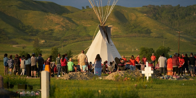Hundreds of people gather for a vigil in a field where human remains were discovered in unmarked graves at the site of the former Marieval Indian Residential School