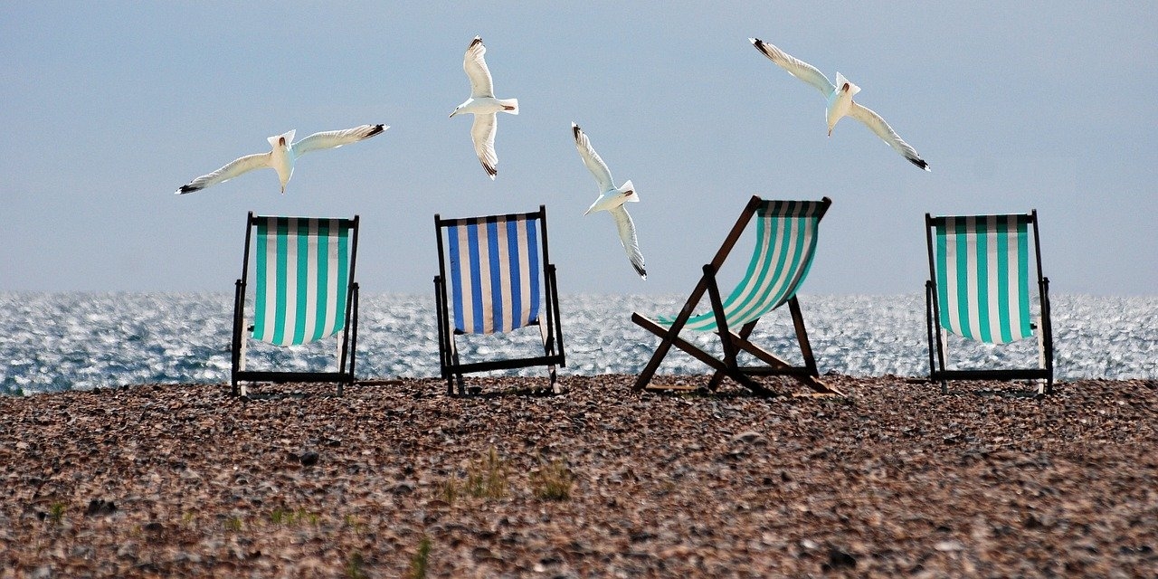 Vier gestreifte Liegestühle an einem Strand