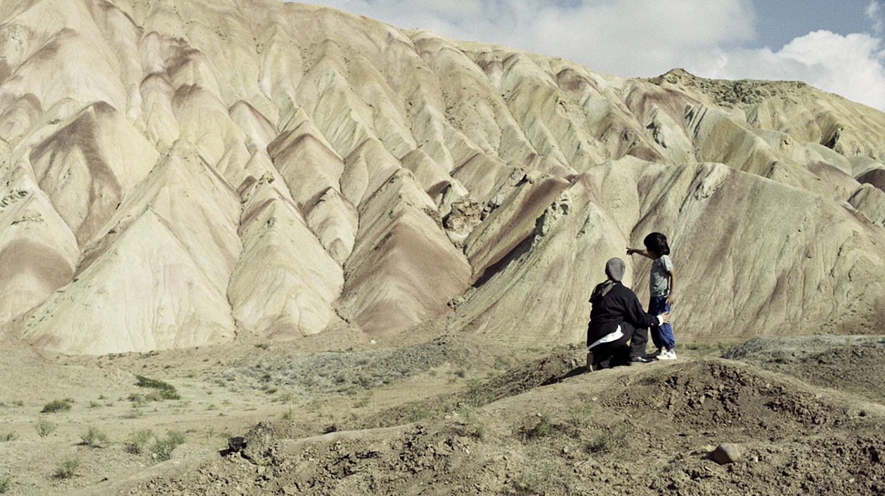 Eine Mutter steht in einer Berglandschaft im Iran. Filmszene aus "Hit the Road".