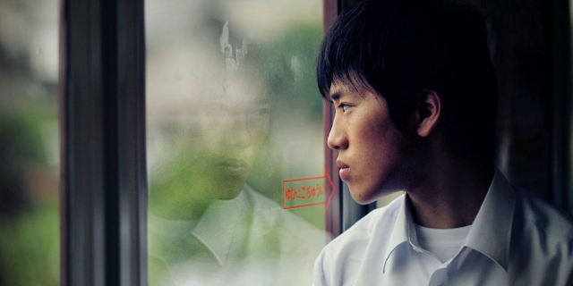Japanischer Jugendlicher blickt durch Zugfenster
