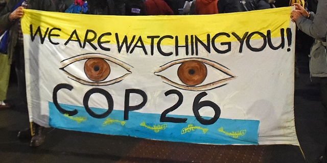 Demoplakat auf der Klimakonferenz - zwei Augen mit der Aufschrift "COP26 - we are watching you"