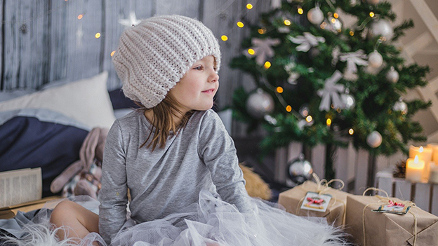 Kind unter Weihnachtsbaum mit Geschenken