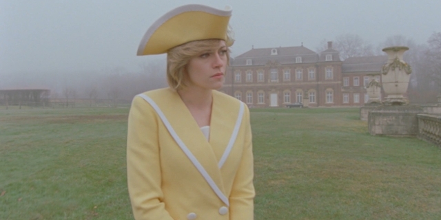 Kristen Stewart als Diana im gelben Kostüm, schaut traurig. Eine Szene aus "Spencer".