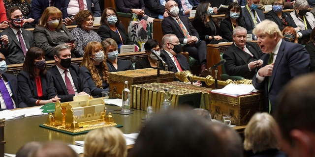 Tory-Überläufer Christian Wakeford mit Union-Jack-Schutzmaske inmitten von Labour-Abgeordneten im englischen Unterhaus während Boris Johnson spricht.