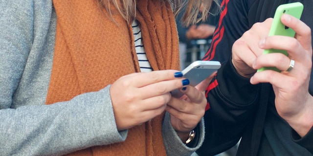 Ein junger Mann zeigt einer jungen Frau etwas auf seinem Smartphone.