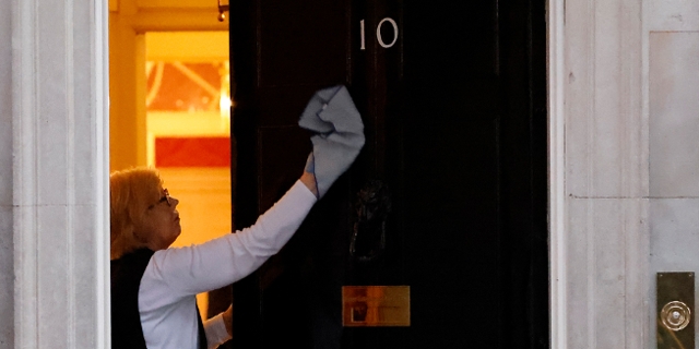 A cleaner wipes the door at Number 10 Downing Street in London on February 7