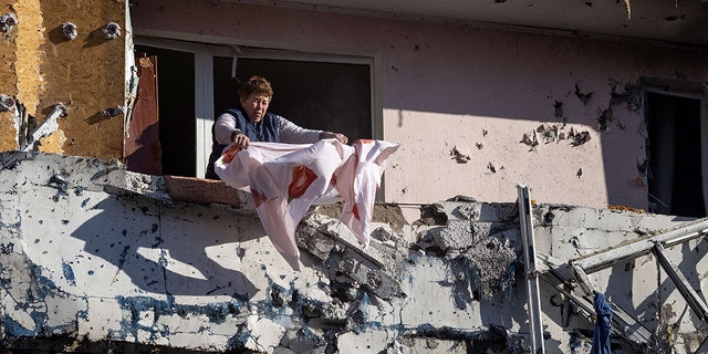 Bürgerin in Kiew kümmert sich um ihre Wäsche, das Haus ist von Schüssen und Explosionen zertrümmert