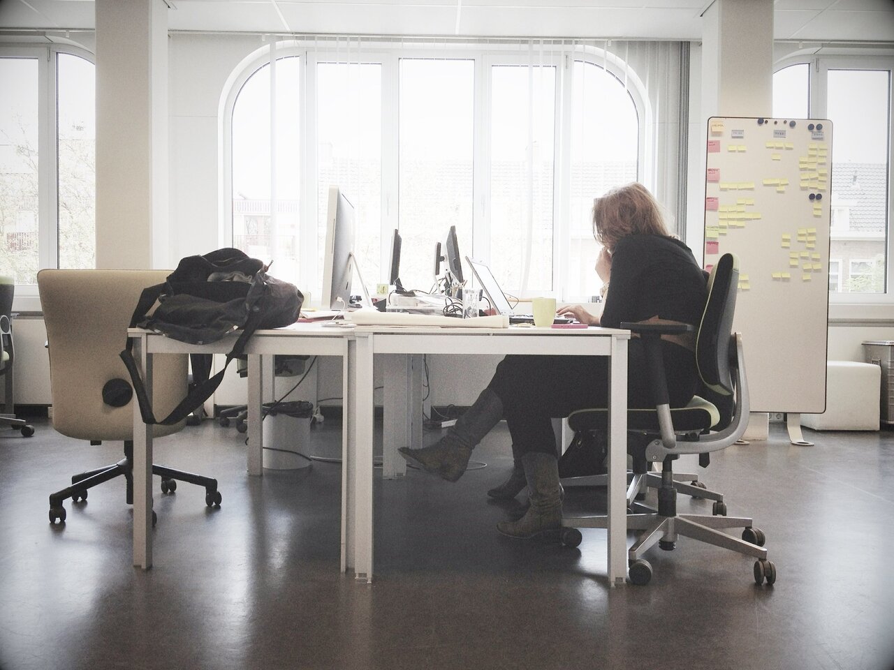 Eine Bürosituation, rechts eine Frau vor einem Computer.