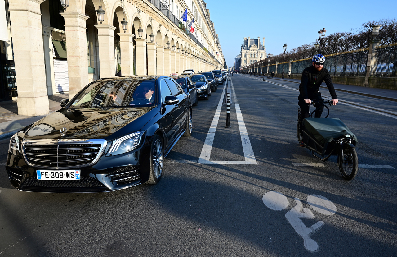 A cyclist on a bicycle path makes his way past a row of cars waiting
at a red light along the rue de Rivoli in Paris on March 8, 2022.