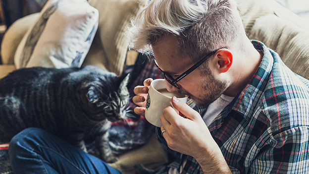 Mann trinkt Kaffee mit Katze