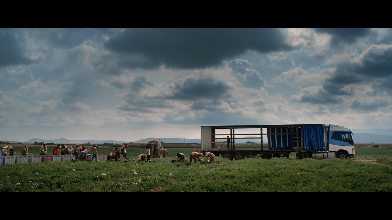 Ein Lkw steht auf einem Feld, wo Arbeiter Melonen ernten. Szene aus der Doku "A Parked Life" von Peter Triest.