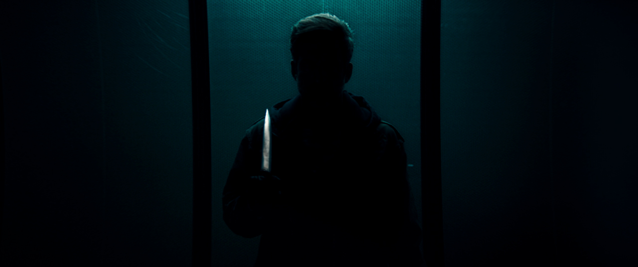 Screenshot aus dem neuen Film von Dario Argento: Person in einem finsteren Raum mit einem Messer in der Hand