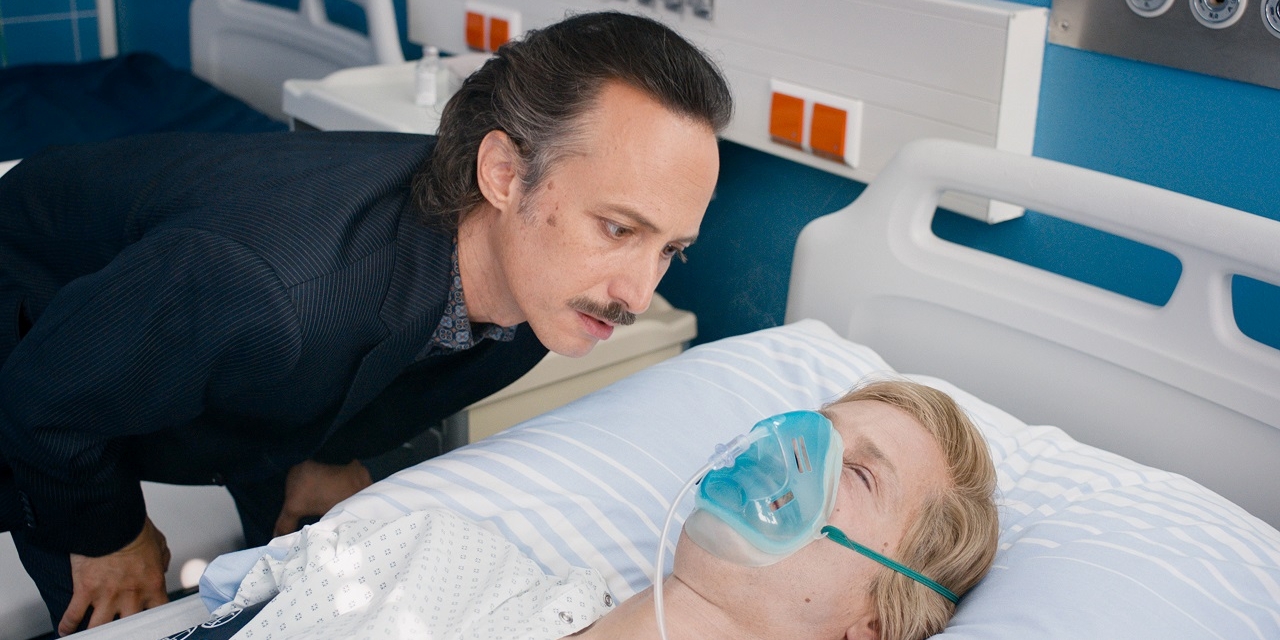 Michael Ostrowski beugt sich über einen Mann im Krankenbett. Szene aus "The Hawk/Der Onkel".