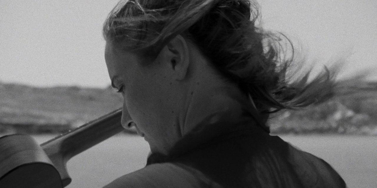 Junge Frau auf einem Segelboot am Meer, das Haar weht im Wind. Szene aus "Stories from the Sea".