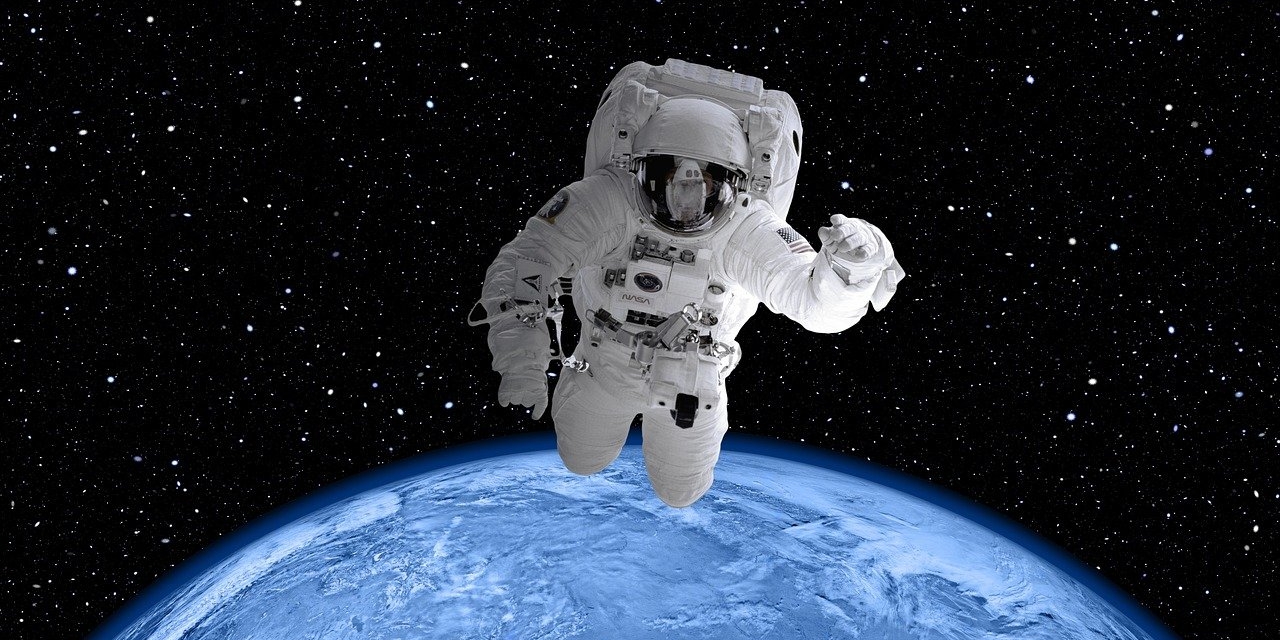 Astronaut*in im Weltraum vor Erdkugel