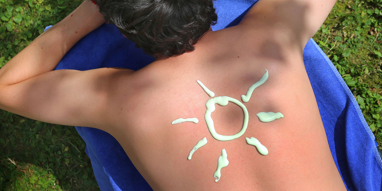 Mann mit Sonnencreme in Sonnenform am Rücken