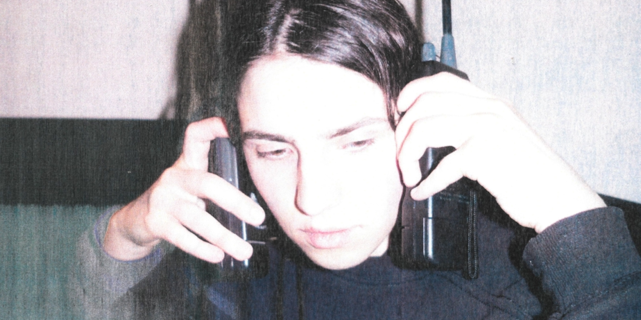 Eine Person mit zwei großen, alten Handys an den Ohren