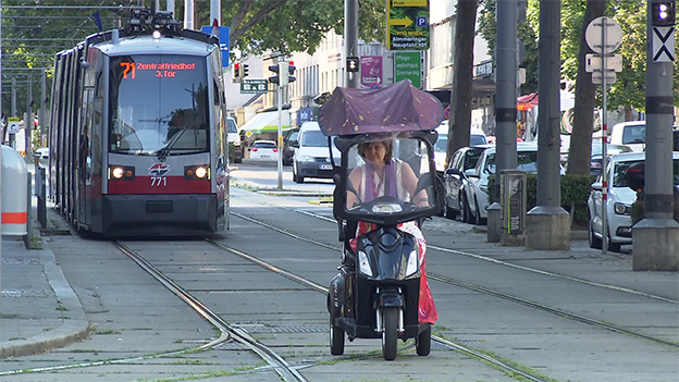 Frau mit Roller vor Strassenbahn